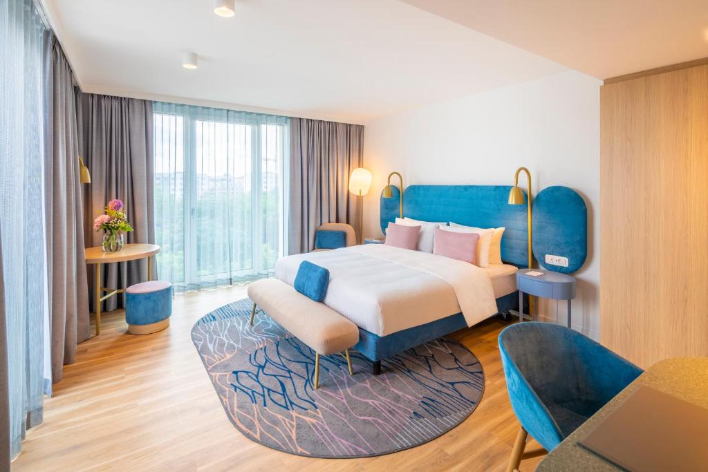 - une chambre avec un grand lit et un mobilier bleu dans l'établissement Capri by Fraser Leipzig, à Leipzig