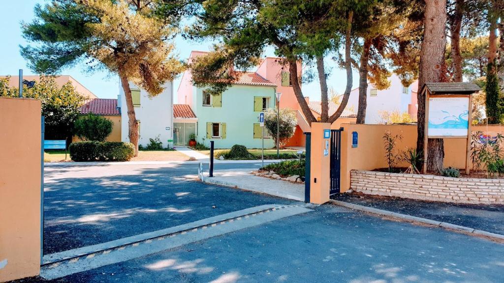 a house with a gate in a street with trees at Village Club Thalassa in Mèze