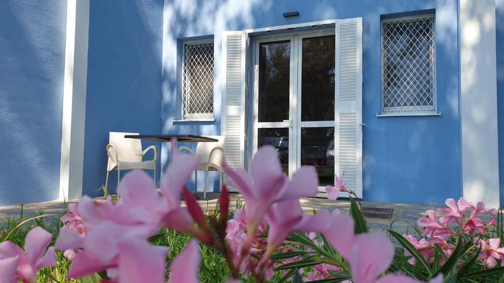 una casa azul con flores rosas delante en IL SOLE NEL MARE - Lido di Volano, en Comacchio