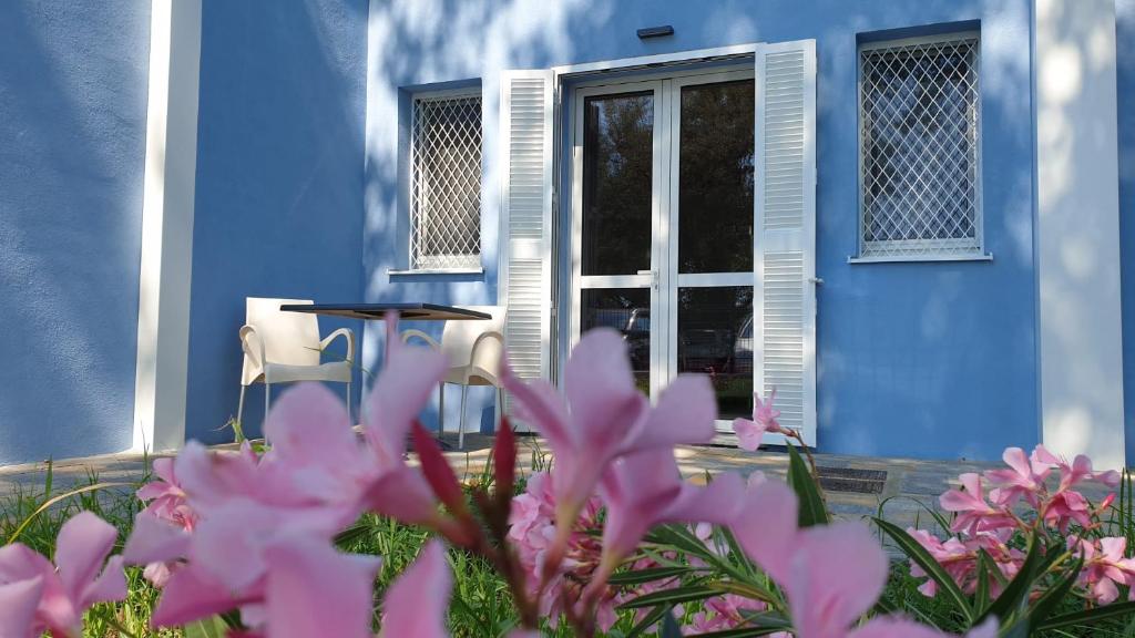 Uma casa azul com flores cor-de-rosa à frente. em IL SOLE NEL MARE - Lido di Volano em Comacchio