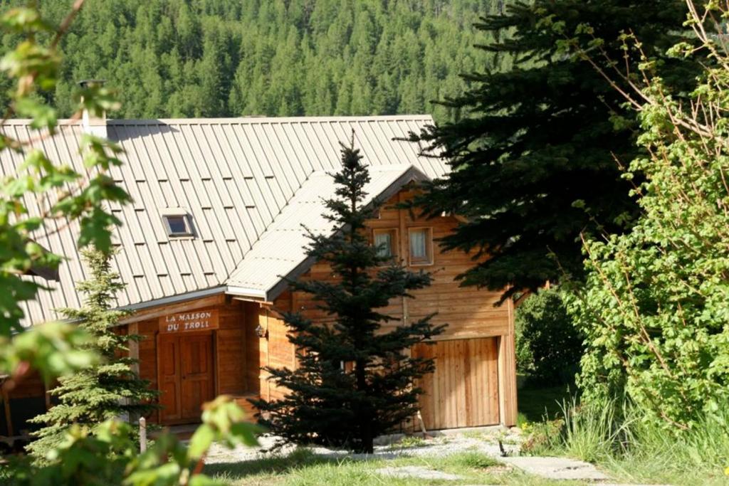 a wooden house with a garage and a tree at Le Troll Hameau des Chazals Nevache Hautes Alpes in Névache