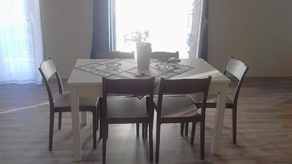 una mesa de comedor blanca con sillas y un jarrón. en Case marino, en Termini Imerese