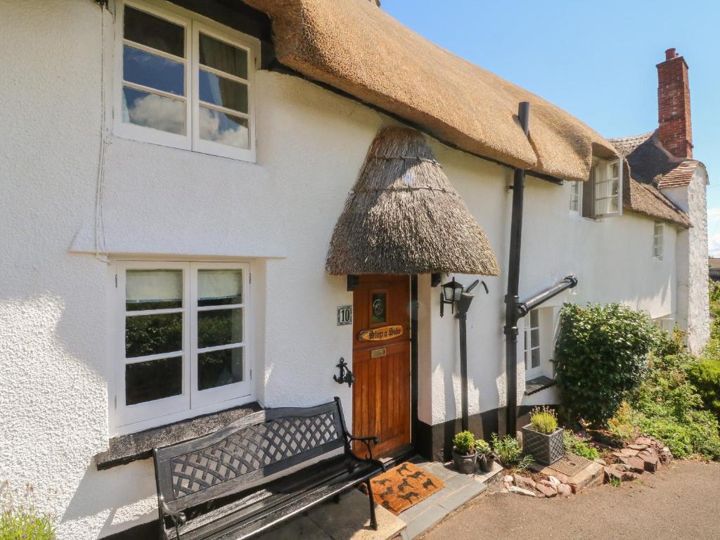 a thatched cottage with a bench in front of the door at Step a Side in Minehead