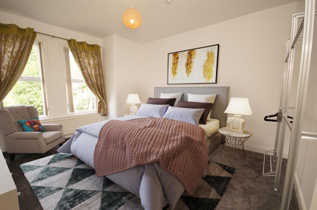a bedroom with a bed and a chair and windows at Grosvenor Lodge Birkdale in Southport
