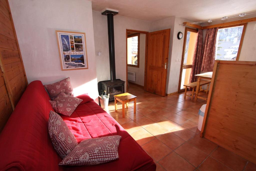 a living room with a red couch and a fireplace at Le Leyrier Hameau des Chazals Nevache Hautes Alpes in Névache