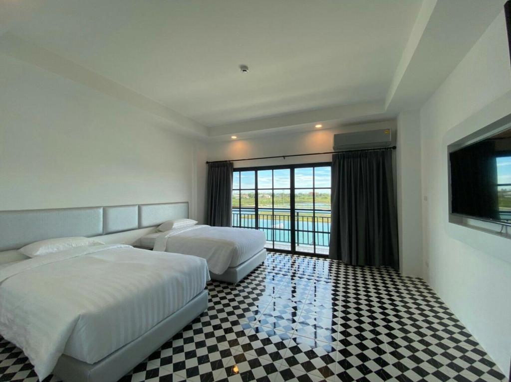 a hotel room with two beds and a window at ESC PARK HOTEL in Pathum Thani