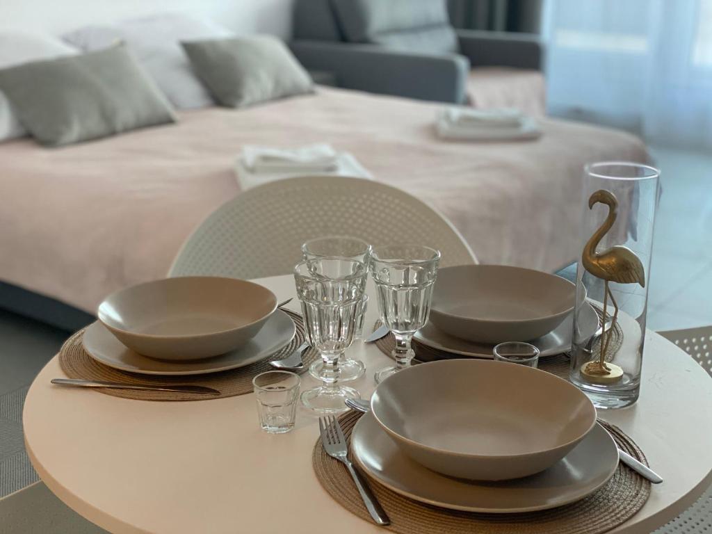 een tafel met borden en glazen op een tafel met een bed bij Aquamarina Prima Gold in Międzyzdroje