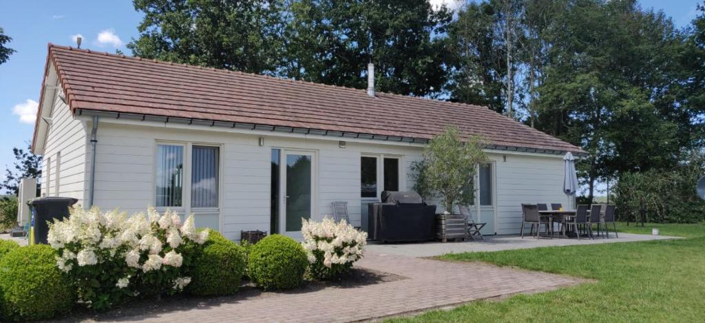 a white house with a table and chairs in a yard at Spitsbroek in Eede