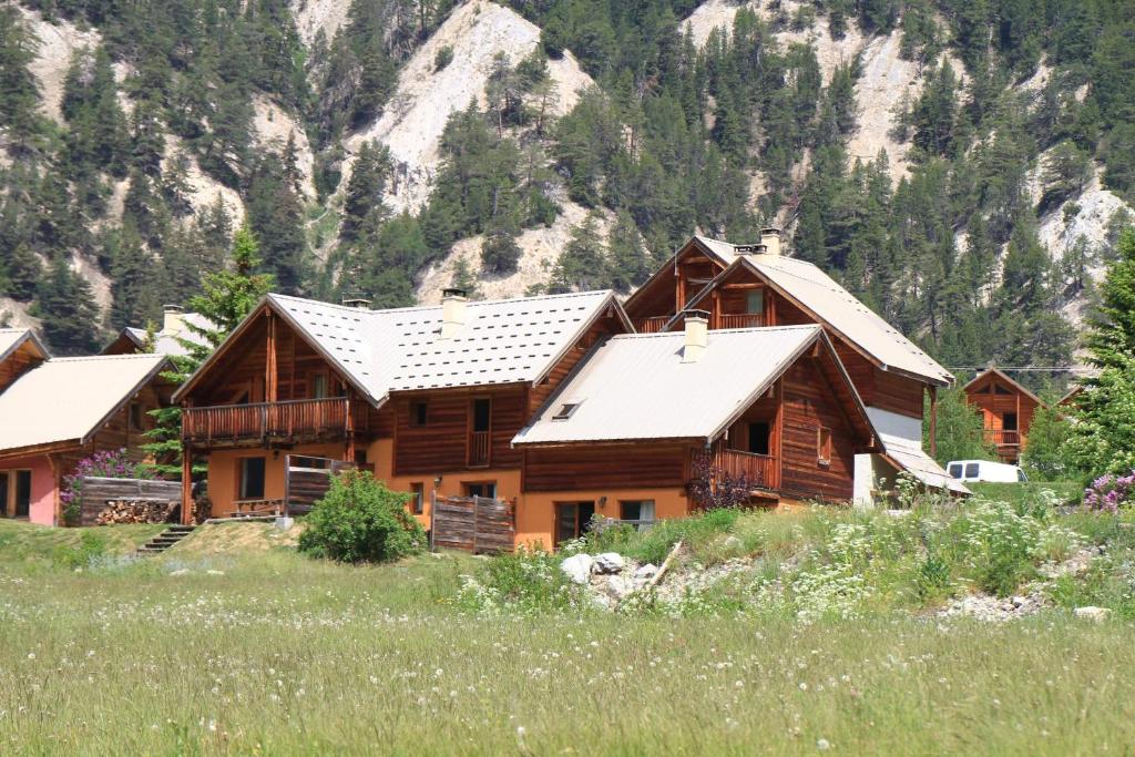 une cabane en rondins avec un champ dans les montagnes dans l'établissement Le Gouroùn Hameau des Chazals Nevache Hautes Alpes, à Névache