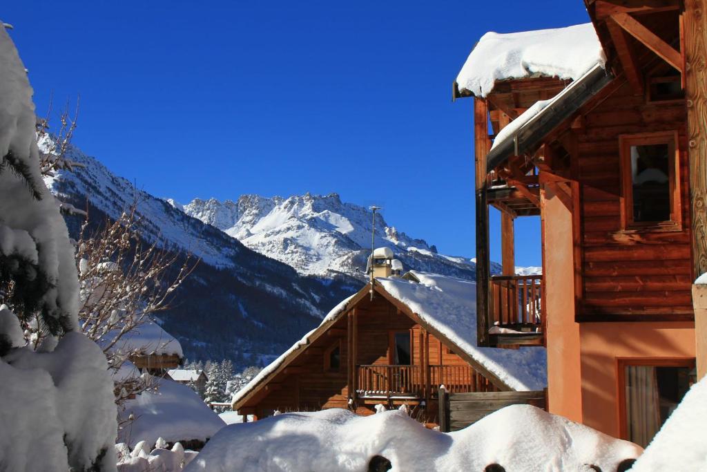 un lodge de ski avec une montagne enneigée en arrière-plan dans l'établissement Le Queyrellin hameau des Chazals Nevache Hautes Alpes, à Névache