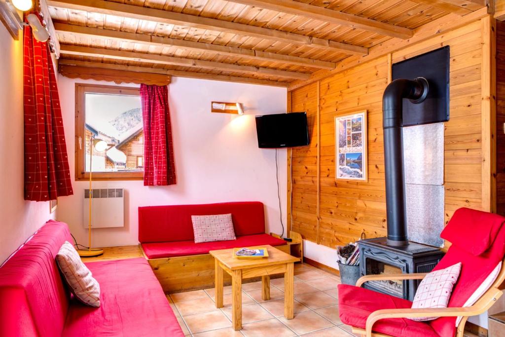 un soggiorno con divano rosso e stufa a legna di Le Pignotto Hameau des Chazals Nevache Hautes Alpes a Névache