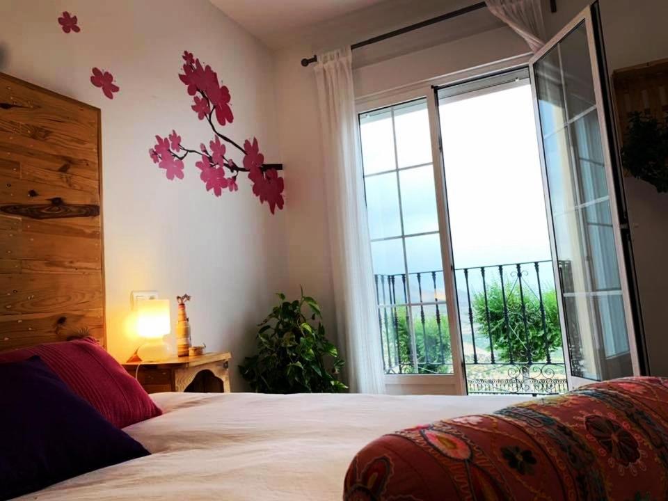 1 dormitorio con cama y ventana grande en La Casa Viva. Alojamiento responsable y sostenible. en Vélez Blanco