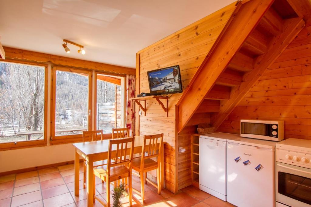 een keuken en eetkamer met een tafel en een tv bij L'Elva Hameau des Chazals Nevache Hautes Alpes in Névache