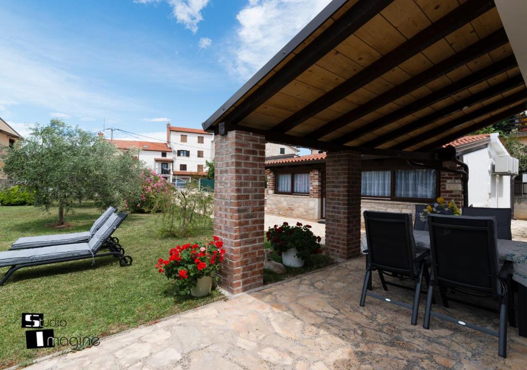 a patio with a table and chairs in a yard at Charming stone cottage by the sea in Umag