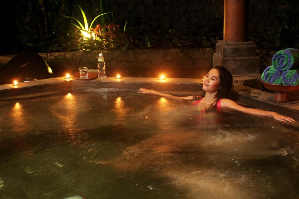 a woman swimming in a hot tub at night at Laras Asri Resort & Spa in Salatiga