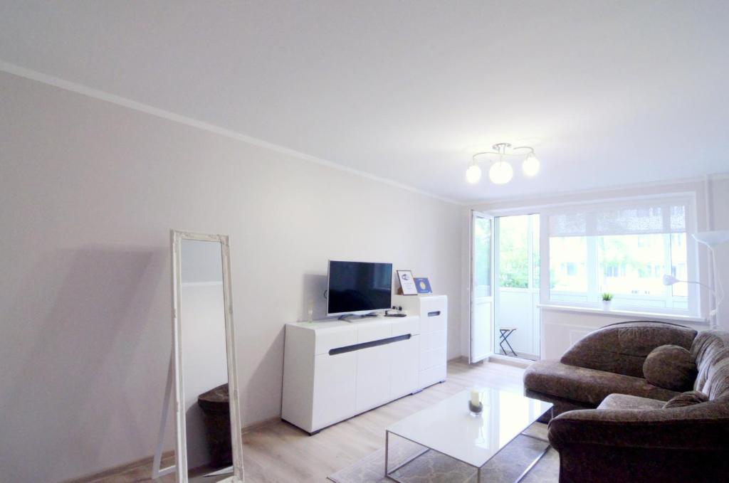 uma sala de estar com um sofá, uma televisão e um espelho em Apartamentai Domeva em Druskininkai