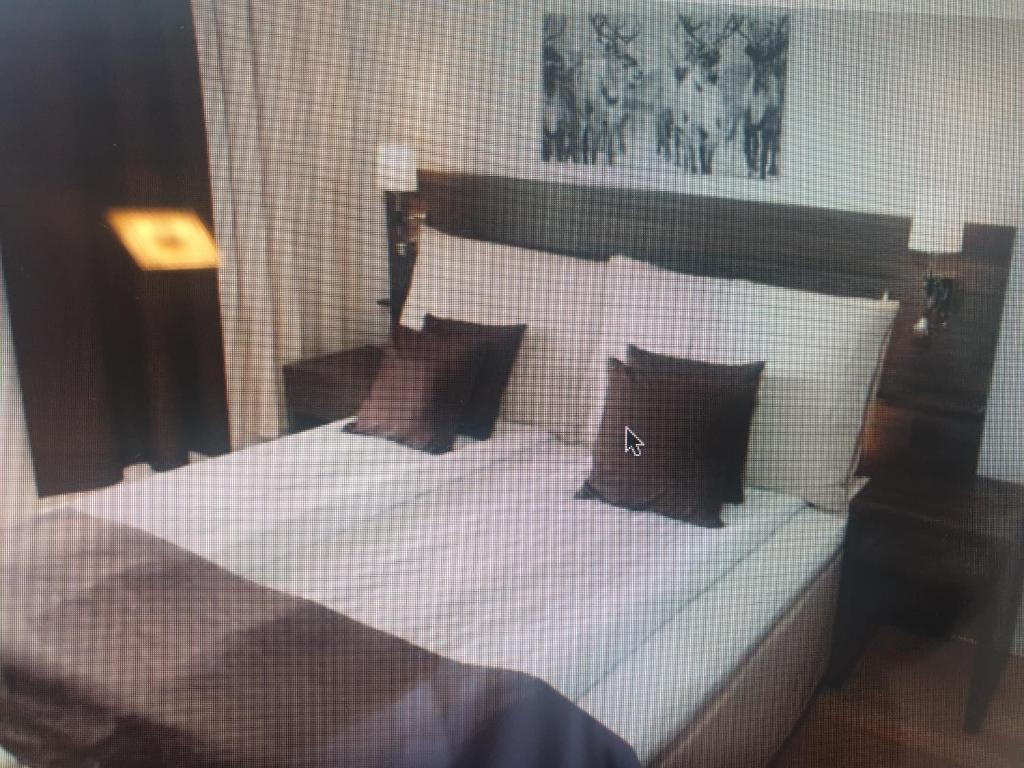 um quarto com uma cama com lençóis brancos e almofadas em Apartement 24, Hotell em Estocolmo