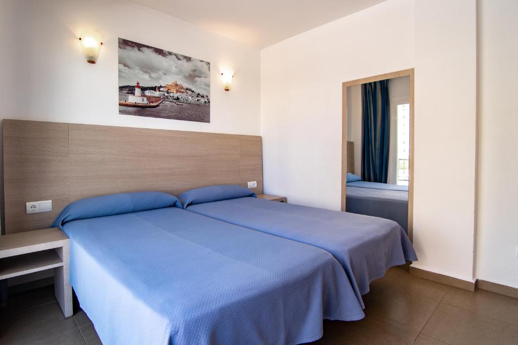 a bedroom with a blue bed and a window at Apartamentos Vistamar II in Playa d'en Bossa