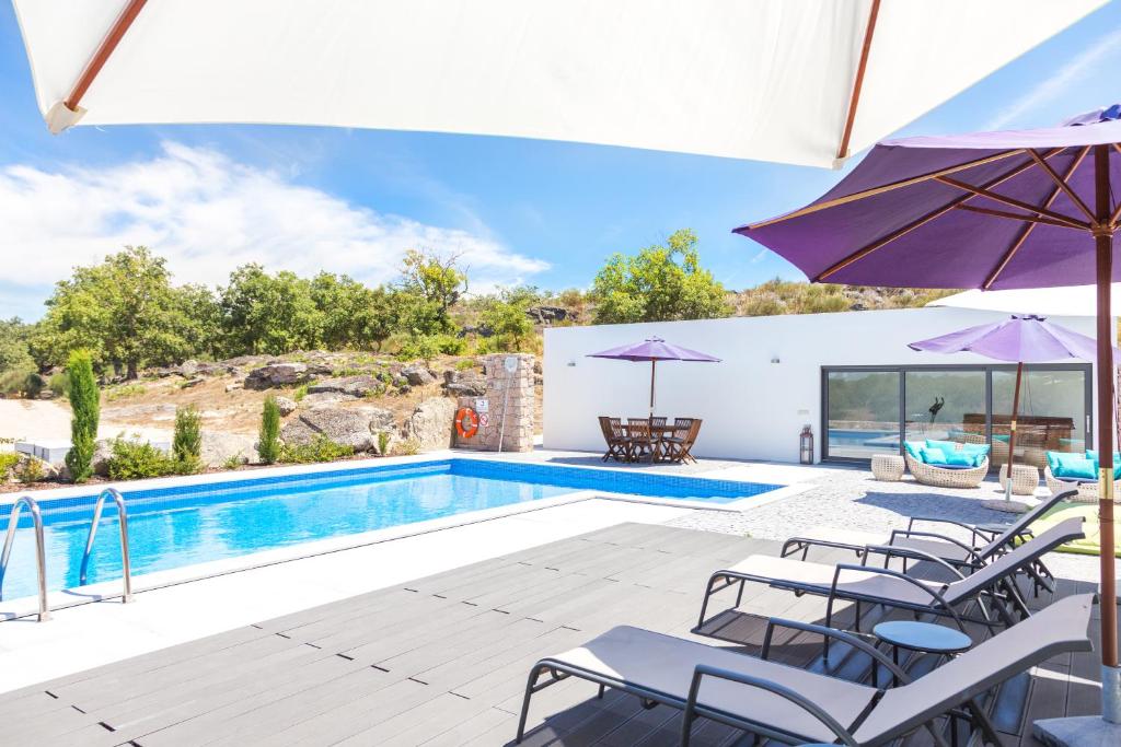 a villa with a swimming pool with chairs and umbrellas at Quinta das Lavandas in Castelo de Vide