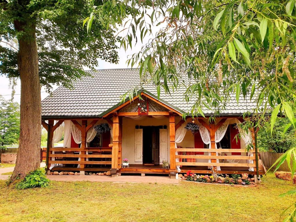 Casa de madera con porche y árbol en Klimatyczna Willa w stylu BOHO, en Wysokie Mazowieckie
