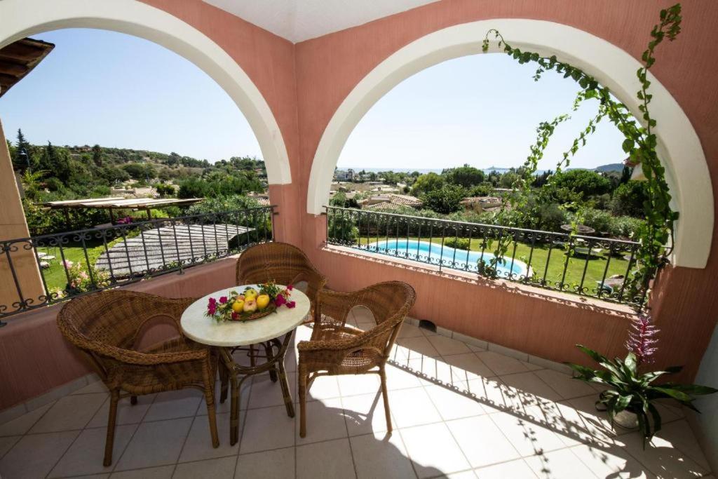 a balcony with a table and chairs and a pool at Hotel Mariposas in Villasimius