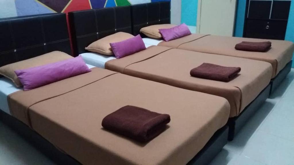 três camas num quarto com almofadas roxas em Manja Inn, Paka em Paka