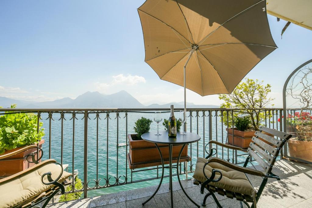 eine Terrasse mit einem Tisch, Stühlen und einem Sonnenschirm in der Unterkunft Giulia in Verbania
