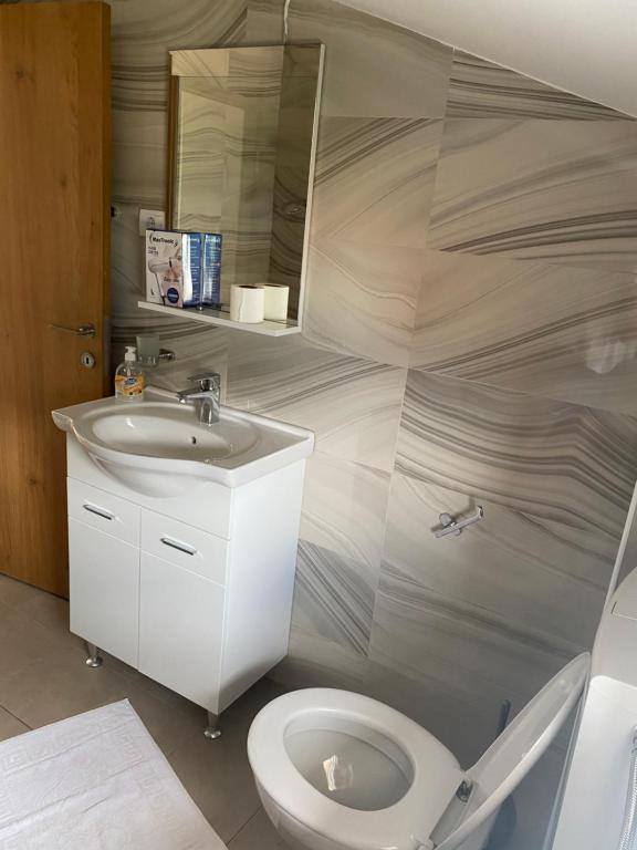 a bathroom with a white toilet and a sink at Apartments Boss in Budva