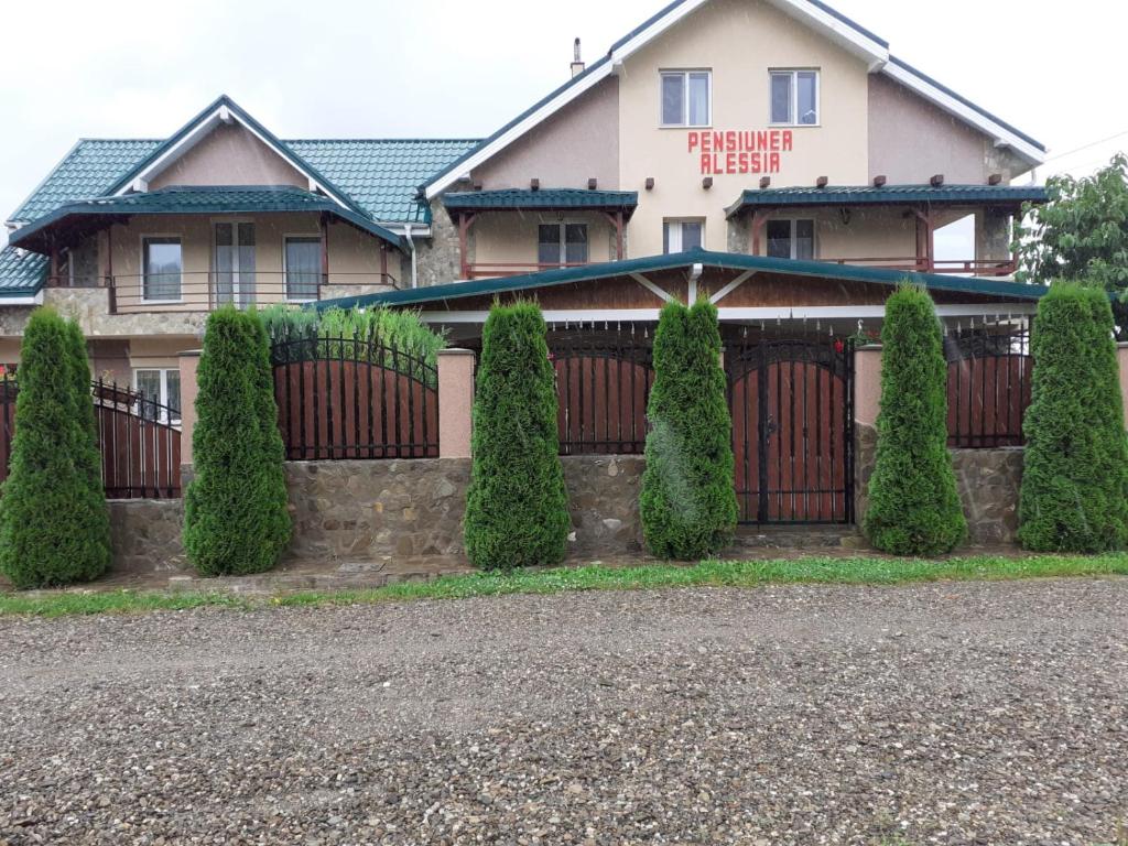 uma casa com uma cerca e sebes à sua frente em Pensiunea Alessia em Piatra Neamţ