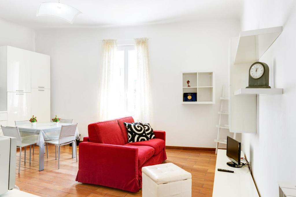 uma sala de estar com uma cadeira vermelha e uma mesa em Migliarina Cozy Apartment em La Spezia