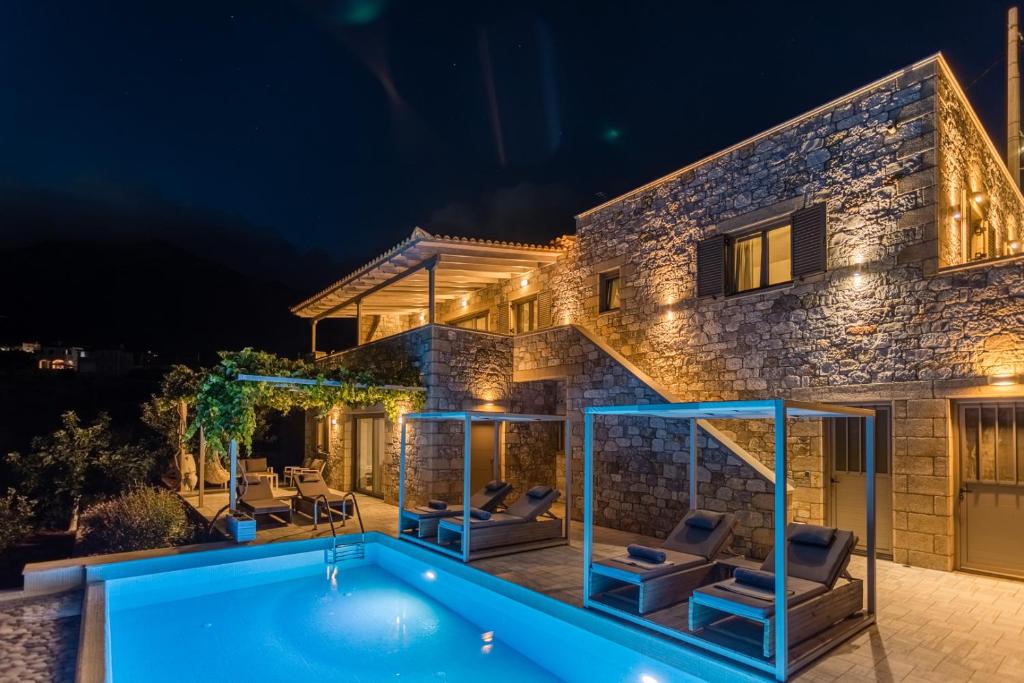 a villa with a swimming pool at night at Villa Achilleas in Stoupa