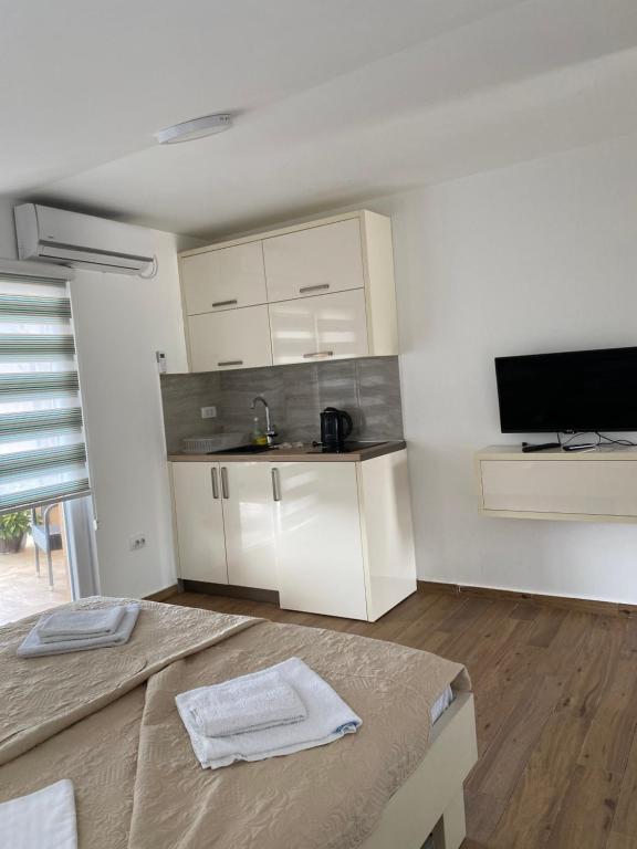 a kitchen with white cabinets and a flat screen tv at Apartments Boss in Budva