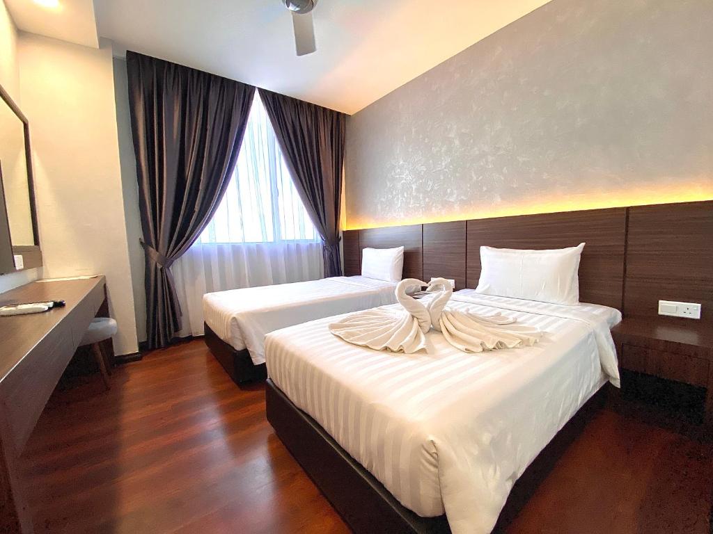 Una habitación de hotel con dos camas con cisnes. en Grace Hotel Semporna en Semporna