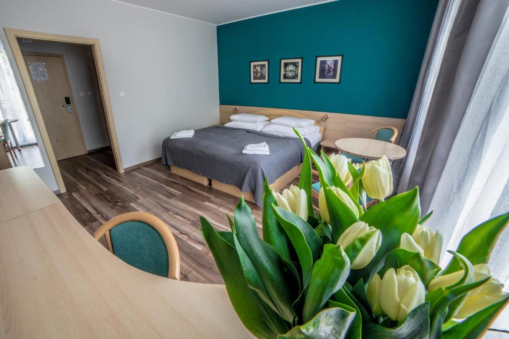 コシツェにあるTeleDom Hotelのベッドと花のテーブルが備わるホテルルームです。