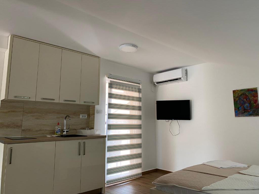 a kitchen with white cabinets and a bed in a room at Apartments Boss in Budva