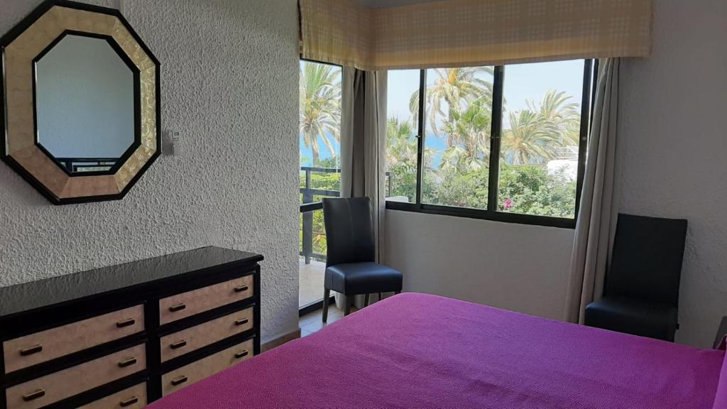 sypialnia z fioletowym łóżkiem i lustrem w obiekcie Skol 134C by Completely Marbella w Marbelli