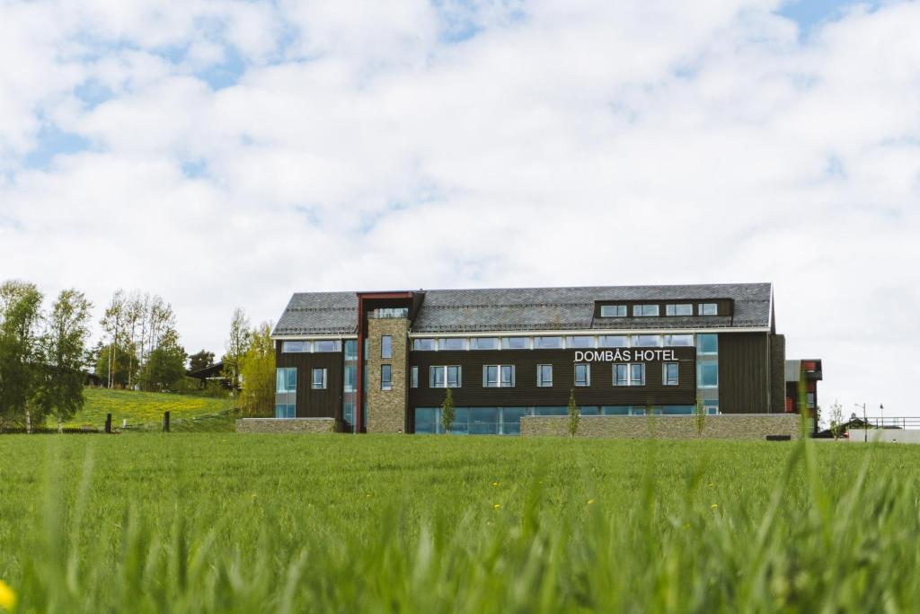 a building with a grass field in front of it at Domb&aring;s Hotel in Domb&aring;s