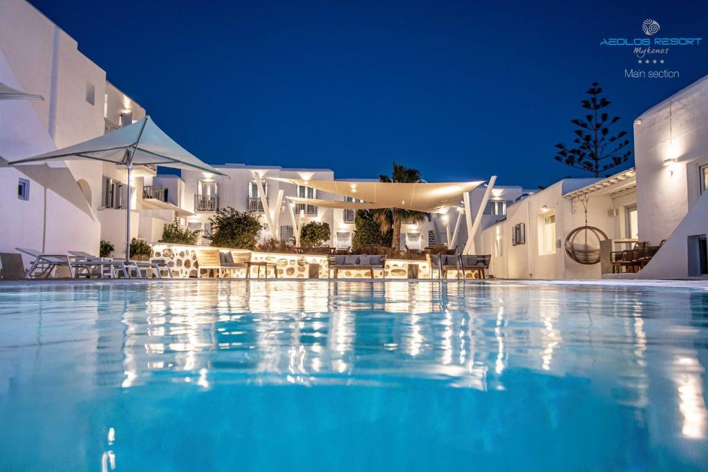 a swimming pool in front of a building at night at Aeolos Resort in Mýkonos City