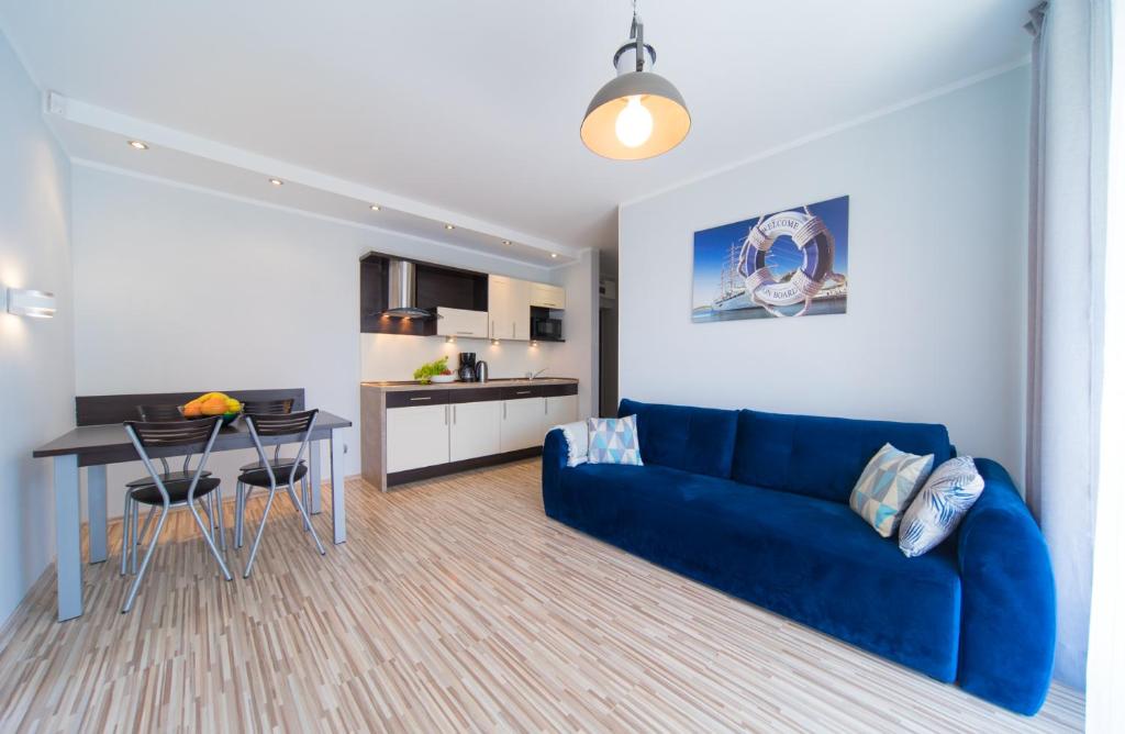 a living room with a blue couch and a kitchen at Aurora Apartament Gardenia in Międzywodzie