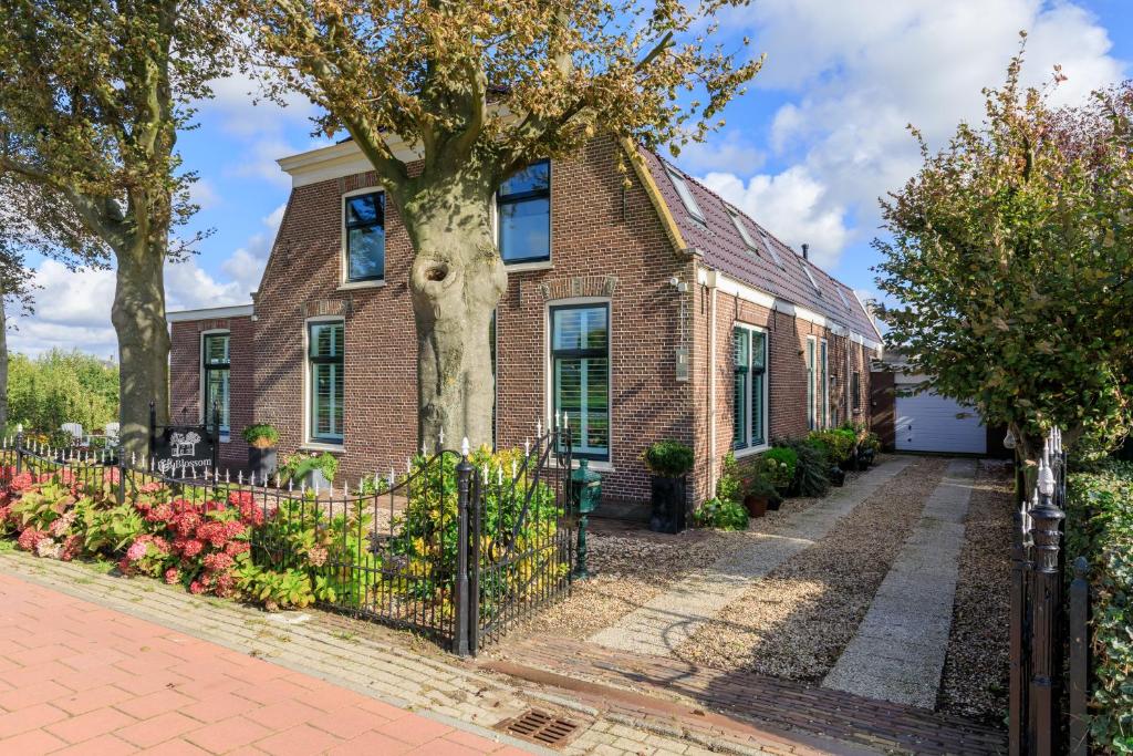 a brick house with a fence and a tree at B&B Blossom in Lisse