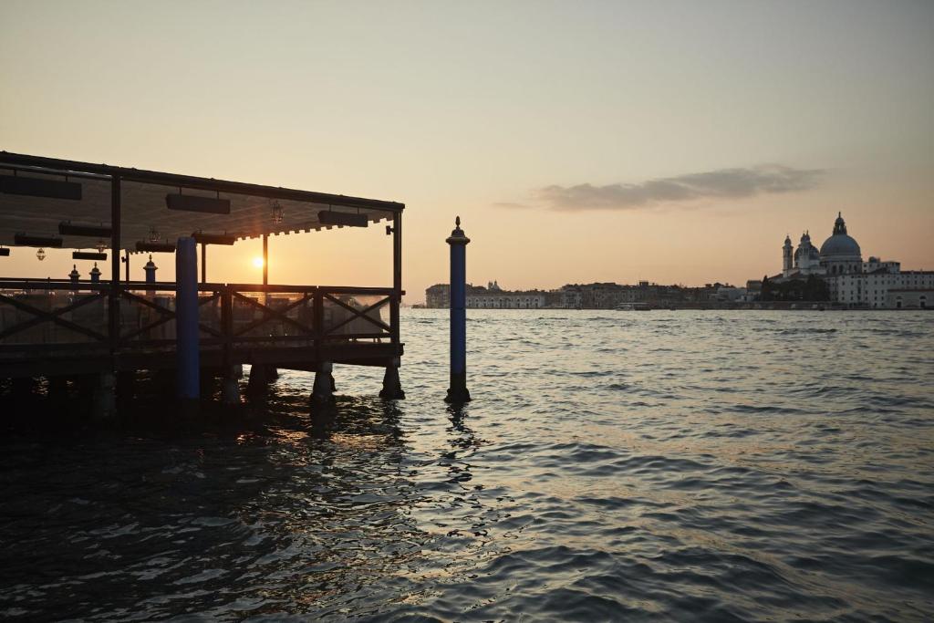 a pier in the water with the sun setting at Hotel Cipriani, A Belmond Hotel, Venice in Venice