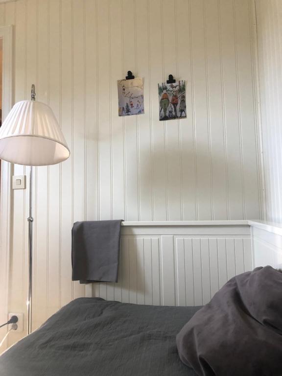 a bedroom with a bed and a lamp and pictures on the wall at Mormors vrå in Mora