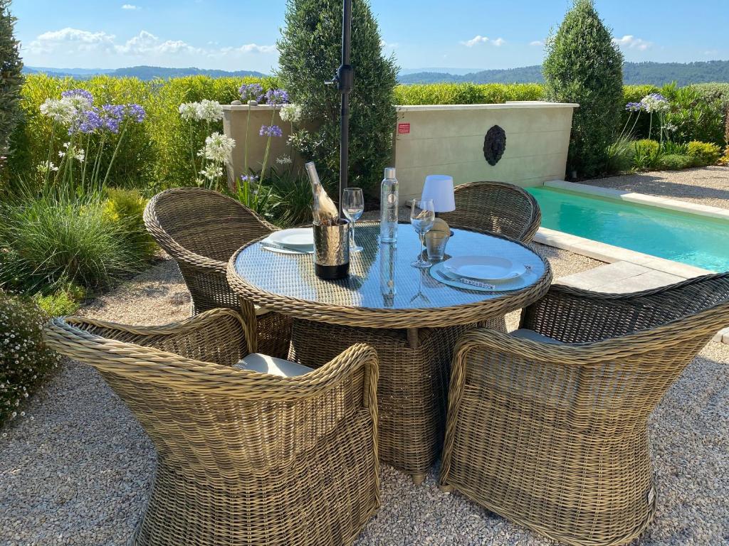 a table with wicker chairs sitting next to a pool at Le Mazet d'Emilia avec jardin et piscine privés in Cucuron