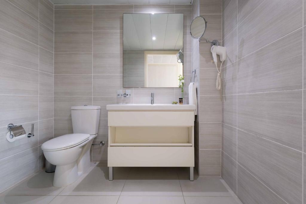 a bathroom with a toilet and a sink and a mirror at Tasia Maris Beach Hotel - Adults Only in Ayia Napa