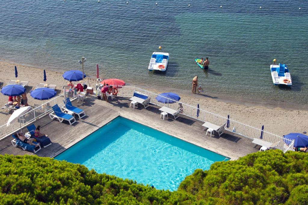 a swimming pool with umbrellas and people on a beach at Hotel Mayola in San Bartolomeo al Mare