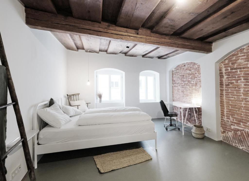 a white bedroom with a bed and a desk at CHARMANTES APARTMENT im Herzen von Linz in Linz