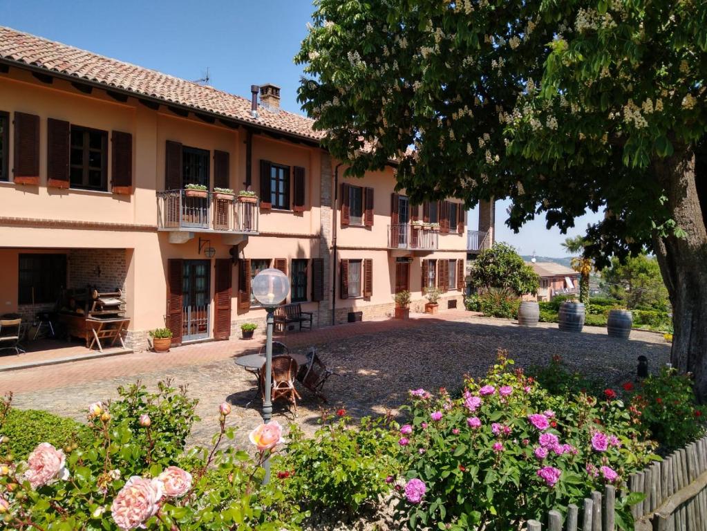 una casa grande con un patio con flores en Agriturismo Cascina del Rosone, en Agliano Terme