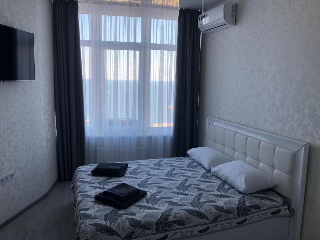 a bedroom with a bed with two black towels on it at Панорамный вид на море 44 Жемчужина Аркадия in Odesa