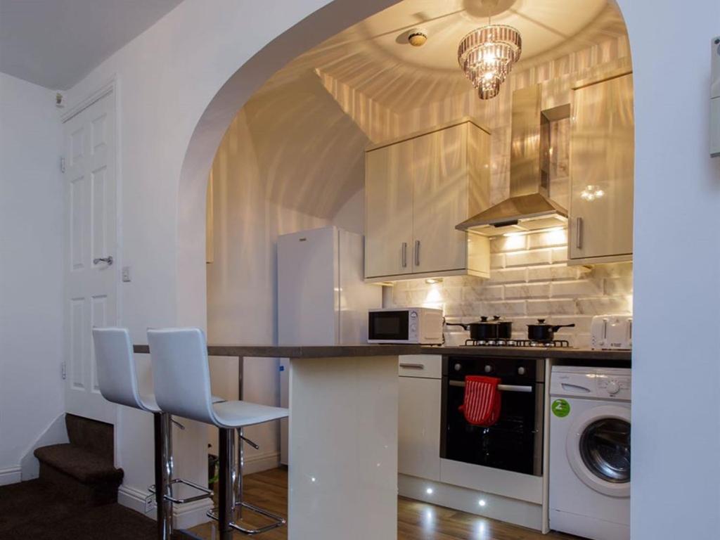 a kitchen with a counter with chairs and a stove at Shaftesbury Apartment in Leeds