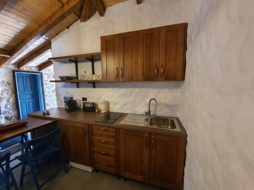 a kitchen with wooden cabinets and a sink at Roots Dhermi in Dhërmi